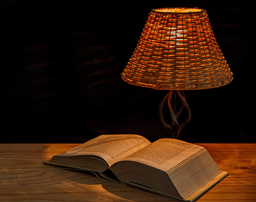 Open Book Under Warm Woven Lamp Light