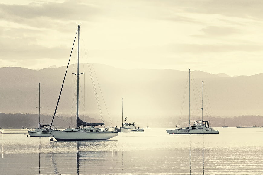 Sailboats Anchored in Calm Harbor with Misty Mountains