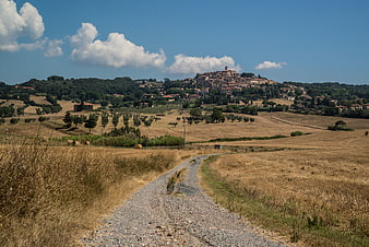 Gravel path leading to medieval hilltop village in Tuscany
