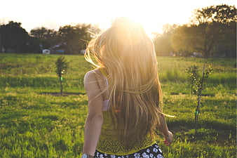 Blonde Woman Running Through Green Field in Golden Sunlight