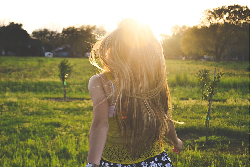 Blonde Woman Running Through Green Field in Golden Sunlight