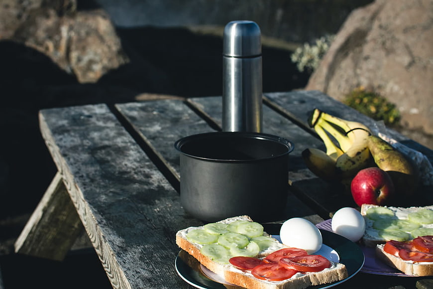 Camping Breakfast with Sandwiches and Fruit on Wooden Table