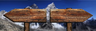Wooden Directional Signpost Against Snowy Mountain Background
