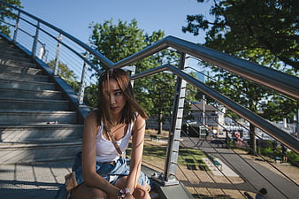 Young Asian Woman Sitting on Urban Stairs in Sunlight