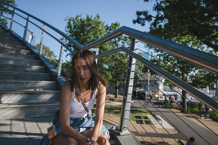 Young Asian Woman Sitting on Urban Stairs in Sunlight