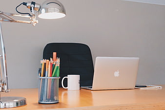 Modern office desk with laptop, lamp, and colorful pencils