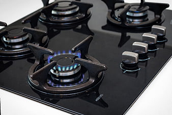 Close-up of black gas stovetop with blue flame