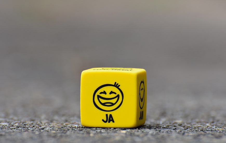 Yellow Dice with Smiley Face and Text on Concrete