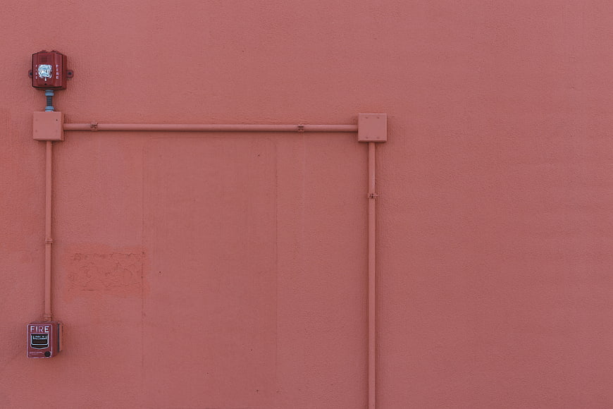 Minimalist Fire Alarm Box On Textured Pink Stucco Wall