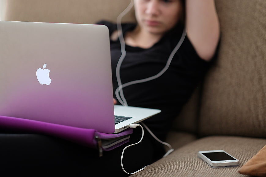 Woman relaxing on sofa with laptop and smartphone