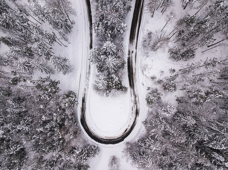 Aerial View of Snowy Forest Road Curve