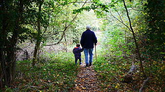 Senior man and young child walking on a forest path