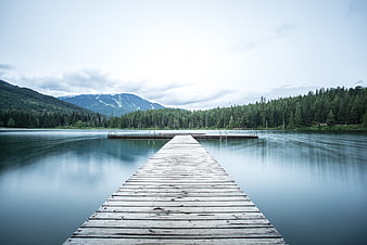Serene wooden pier extending into calm lake with mountains