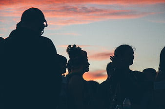 Silhouettes of a crowd watching a colorful sunset sky