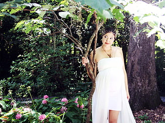 Pregnant woman in white dress standing in garden