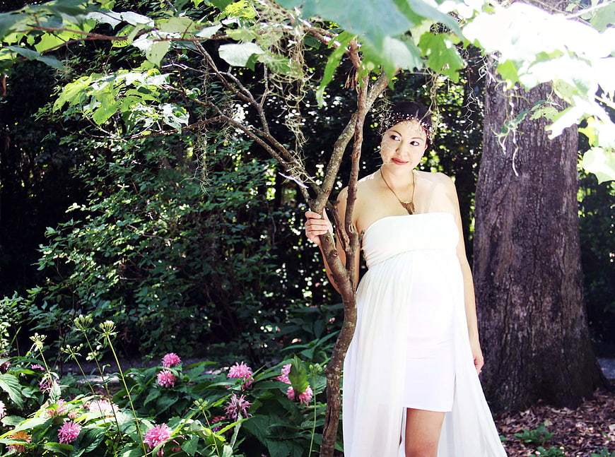 Pregnant woman in white dress standing in garden