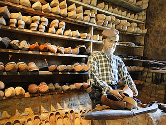 Traditional wooden clog workshop with artisan mannequin and shelves of handmade shoes