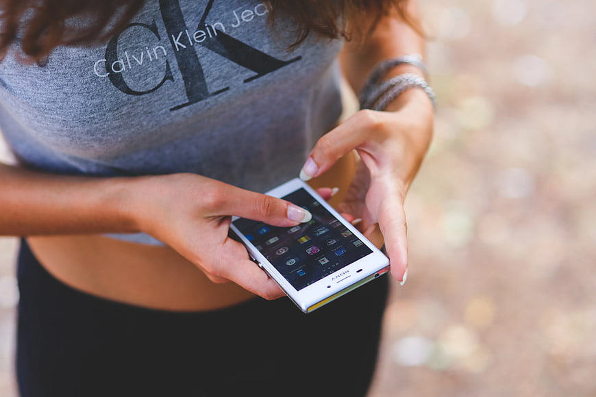 Woman using white smartphone outdoors