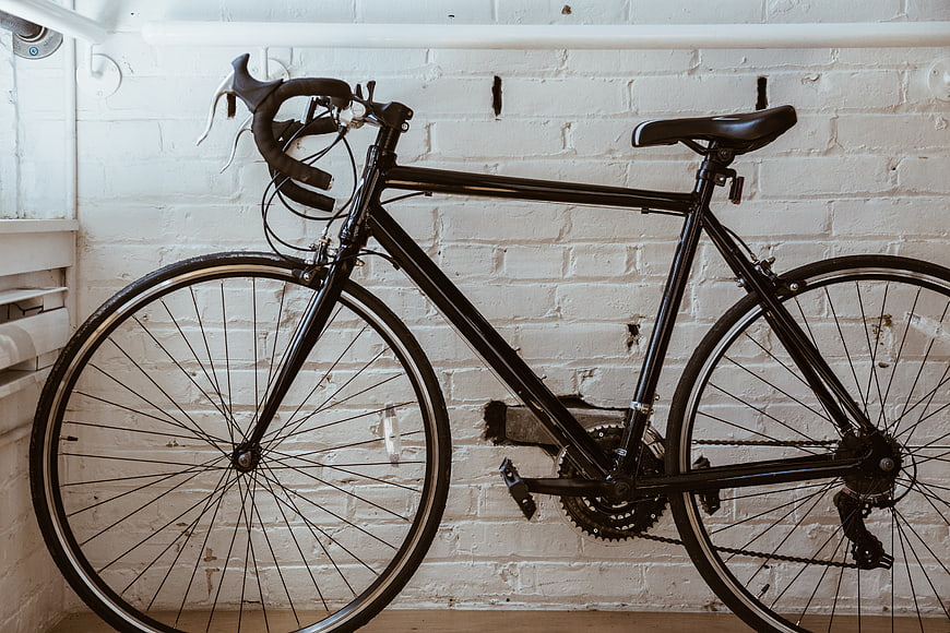 Black Road Bicycle Leaning Against White Brick Wall
