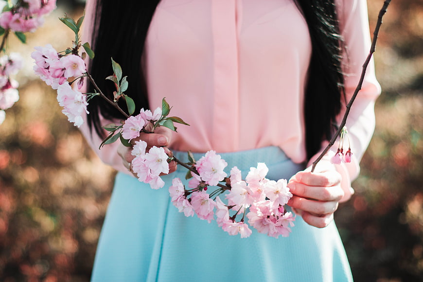 Woman holding pink cherry blossom branch in spring