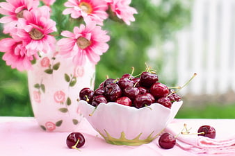 Fresh cherries in a pink bowl with flowers