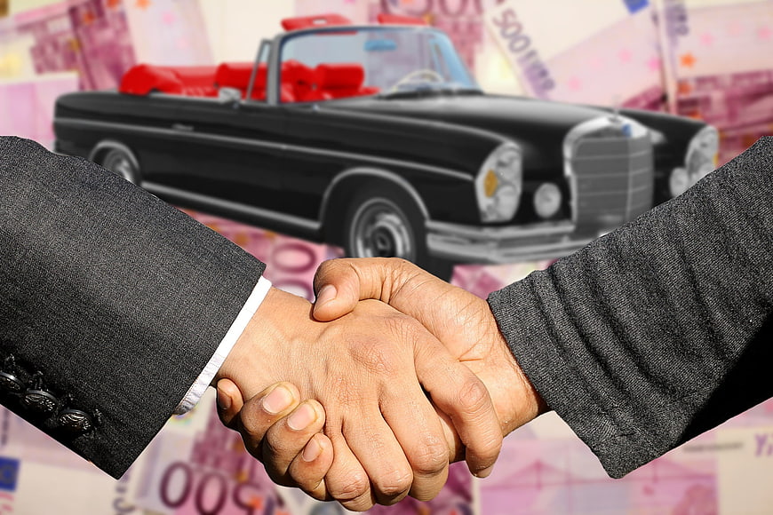 Business handshake over classic car and money background