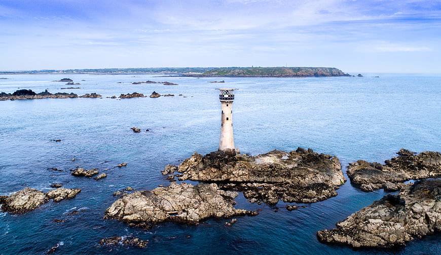 Aerial View of Lighthouse on Rocky Island in Blue Ocean