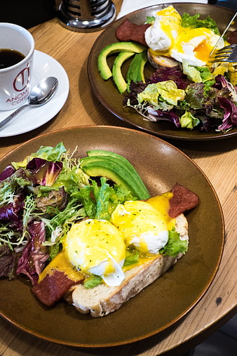 Eggs Benedict with Avocado and Salad on Wooden Table