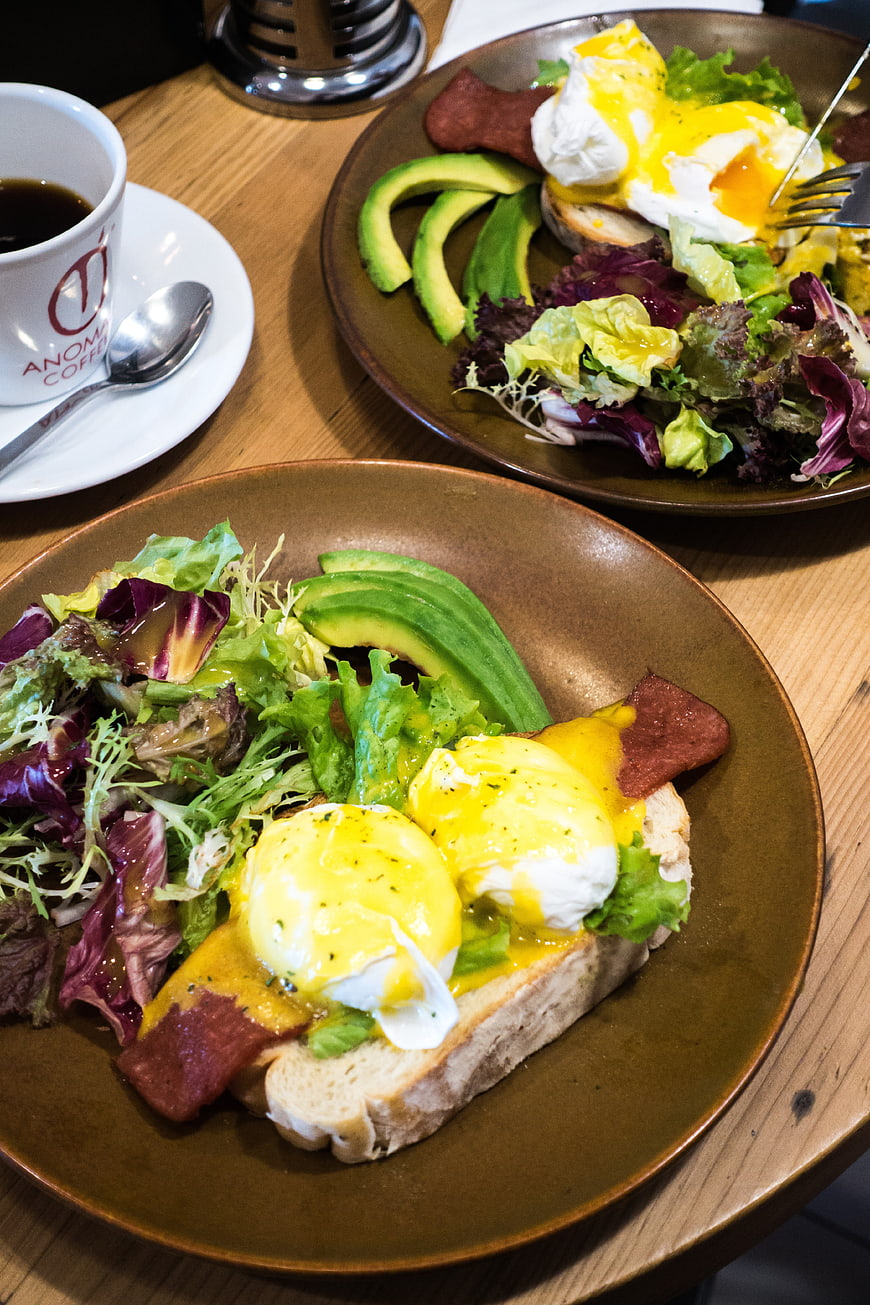 Eggs Benedict with Avocado and Salad on Wooden Table