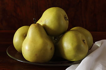 Fresh green pears arranged on a glass plate with rustic background