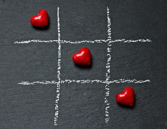 Red hearts playing tic-tac-toe on black slate
