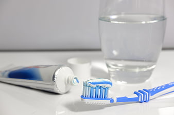 Blue toothbrush with toothpaste and glass of water