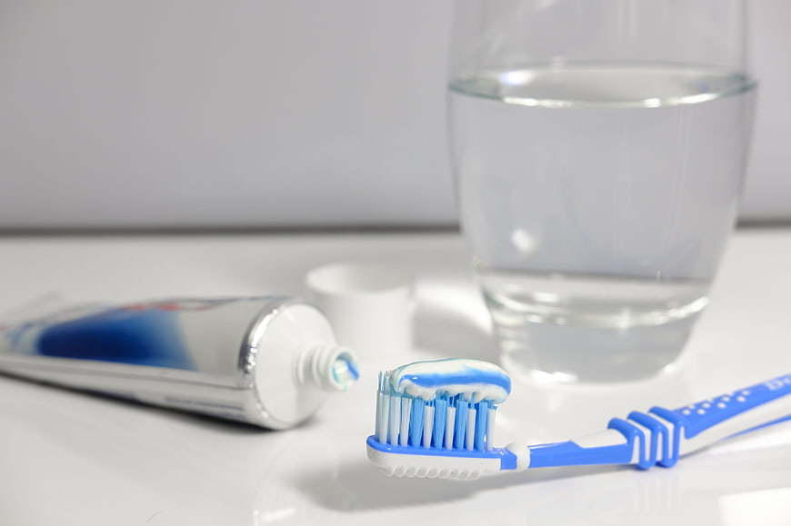 Blue toothbrush with toothpaste and glass of water