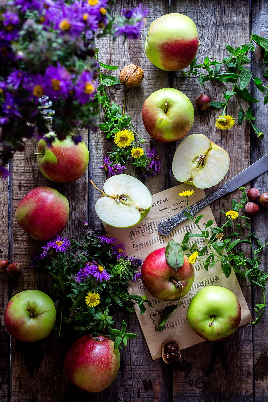 Rustic still life with apples, flowers, and sheet music on wood