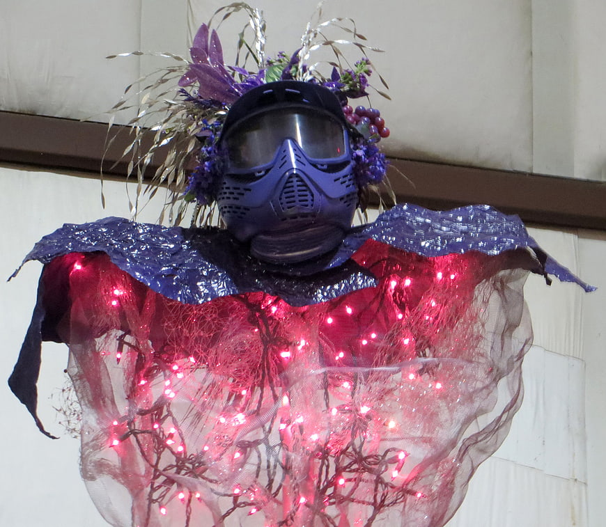 Blue gas mask sculpture with pink lights and flowers