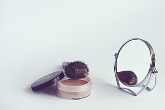 Cosmetic Powder, Brush, and Mirror on White Background