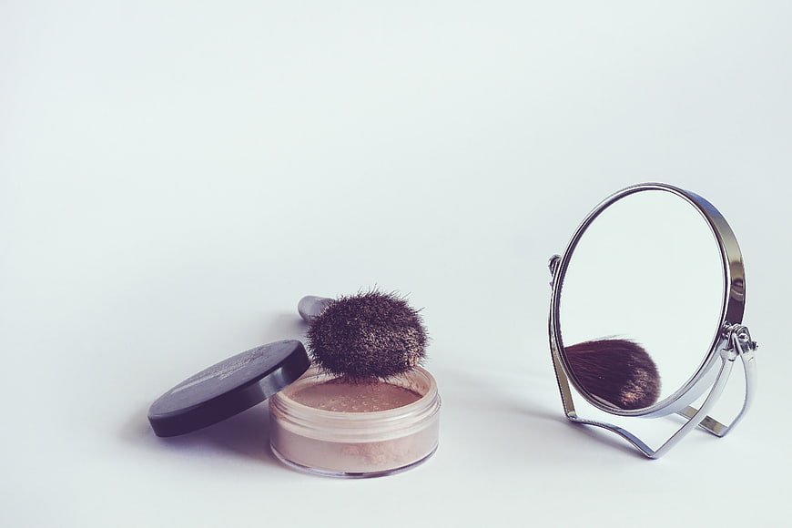 Cosmetic Powder, Brush, and Mirror on White Background