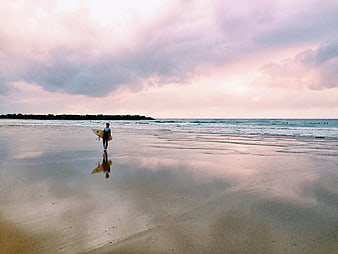 Surfer Walking on Wet Beach at Sunset