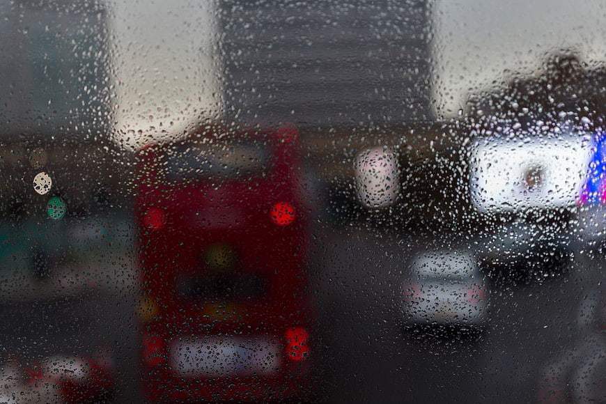 Raindrops on Window with Blurred Red Bus Background