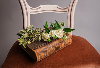 Vintage book with white roses on a brown chair