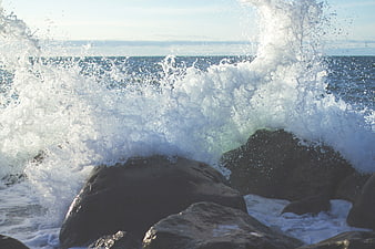 Powerful ocean waves crashing against dark rocks