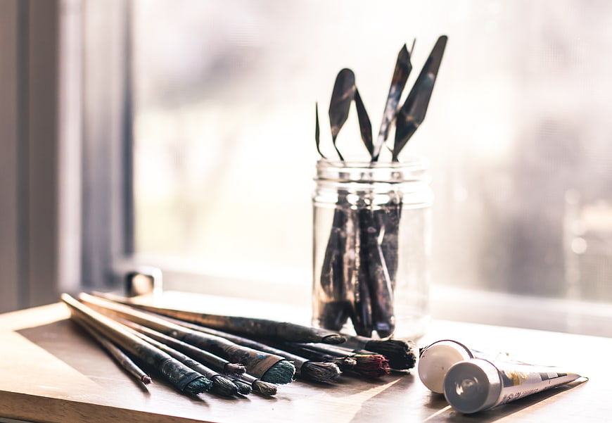 Art supplies on wooden table by window