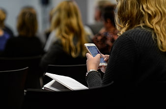 Woman using smartphone in conference audience