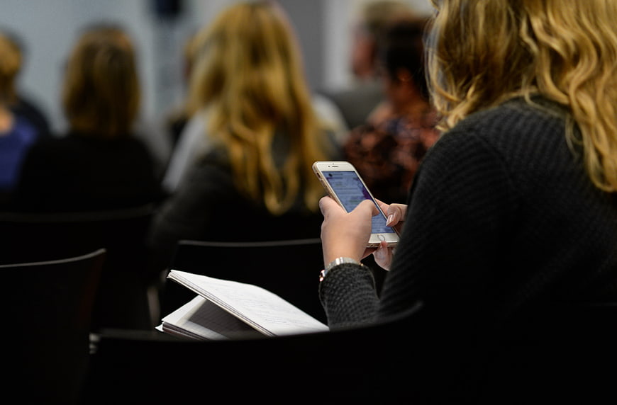 Woman using smartphone in conference audience