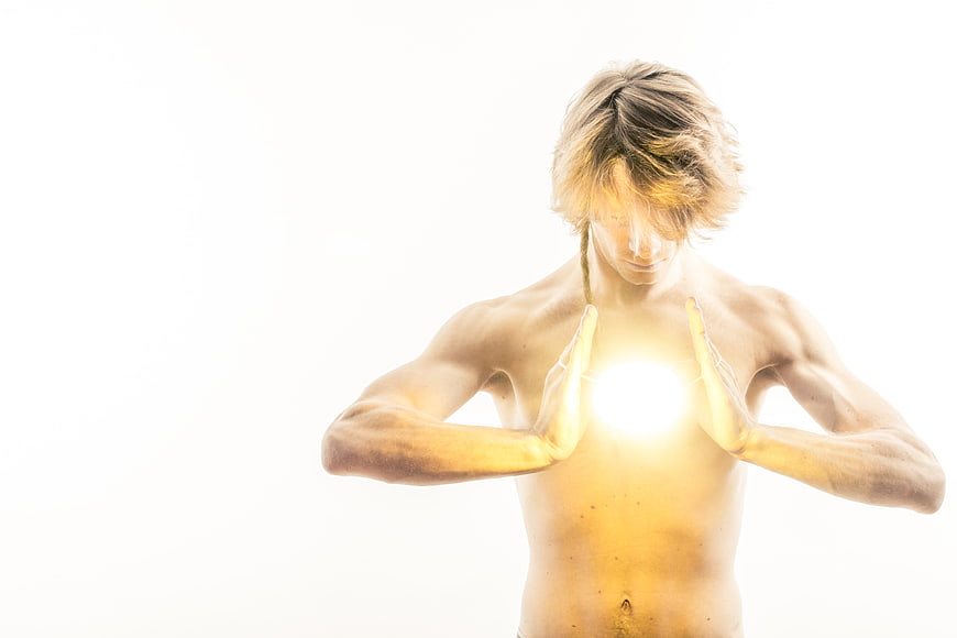 Shirtless Man Holding Glowing Orb Against White Background