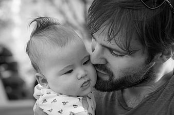 Black and white portrait of a bearded father kissing his baby's cheek