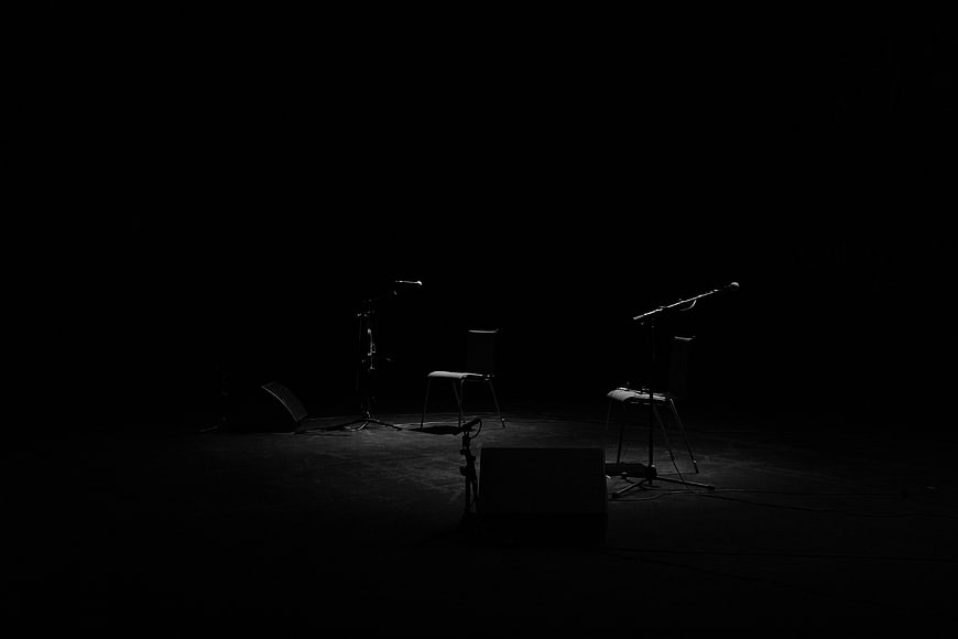 Empty dark stage with microphones and chairs