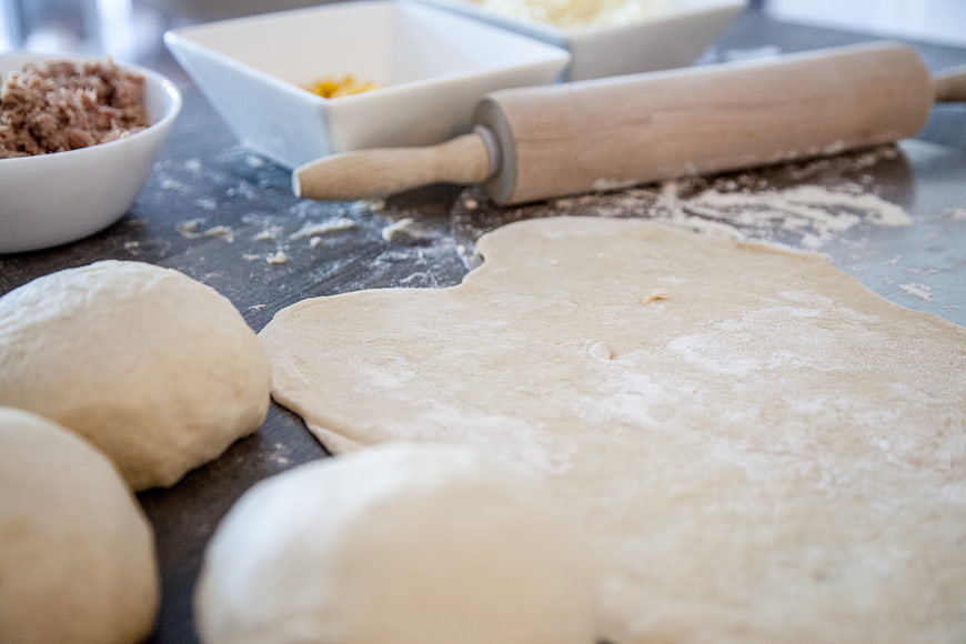 Homemade pizza dough preparation with rolling pin and toppings