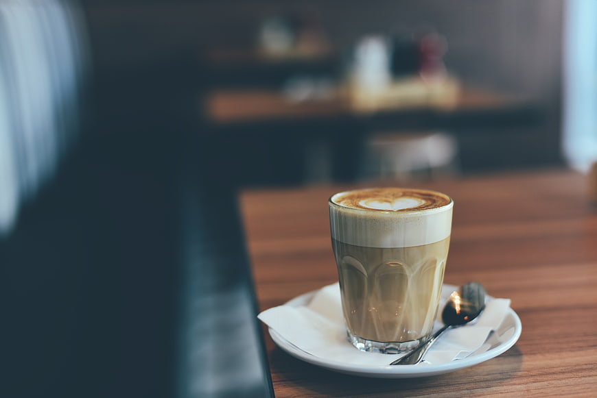 Latte with heart art on wooden cafe table