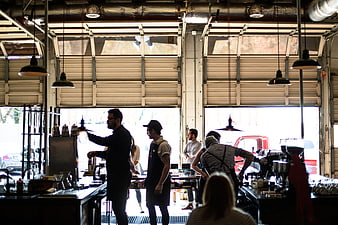 Baristas working in industrial coffee shop with garage doors